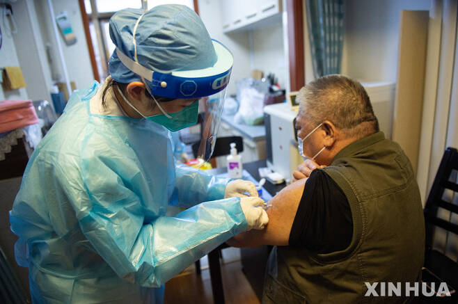 [베이징=신화/뉴시스] 중국 수도 베이징 둥청구에서 주민이 집을 방문한 보건요원에게서 코로나19 백신을 접종받고 있다. 2022.09.29