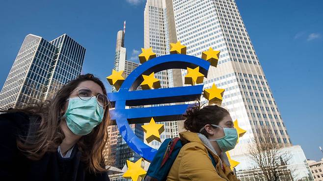 독일 프랑크푸르트에 있는 유럽중앙은행(ECB)의 유로존 상징물 앞을 마스크를 쓴 행인이 지나고 있다. /로이터 연합뉴스