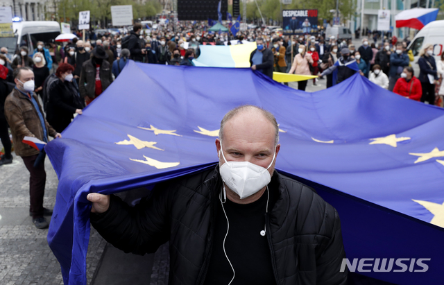 [프라하=AP/뉴시스]29일(현지시간) 체코 프라하에서 마스크를 쓴 시민들이 대형 유럽연합(EU) 깃발을 들고 시위에 참여하고 있다. 이날 수천 명의 시위대가 지난 2014년 러시아 스파이들이 체코의 대규모 탄약고 폭발에 개입했다는 의혹에 대해 밀로시 제만 대통령이 친 러시아적 입장을 취한 것을 두고 '반역'이라고 비난하며 시위를 벌이고 있다. 2021.04.30.