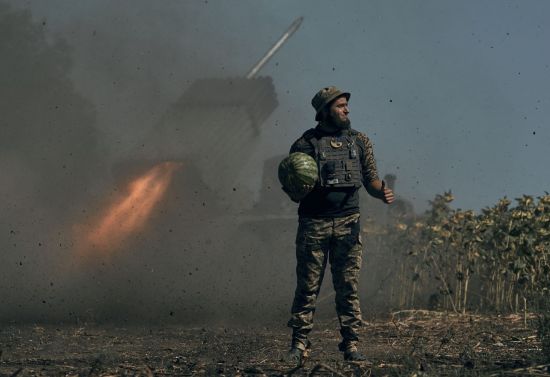 우크라이나 병사가 동부 도네츠크의 전선에서 포격하는 다연장로켓포 옆에 수박을 든 채 엄지를 치켜올리고 있다. [이미지출처=연합뉴스]