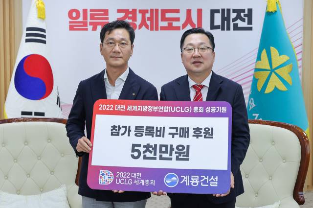 계룡건설 이승찬(왼쪽) 대표가 2022 대전 세계지방정부연합(UCLG) 총회 조직위원장인 이장우(오른쪽) 대전시장에게 일일 참가 등록비 구매비용 5000만원을 전달하고 있다. 사진제공=대전시