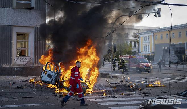 [키이우=AP/뉴시스]10일(현지시간) 우크라이나 수도 키이우에서 한 의료대원이 화재가 발생한 자동차 옆을 지나가고 있다. 이날 러시아가 키이우 등에 미사일 공습을 가하면서 최소 11명이 숨진 것으로 전해졌다. 2022.10.11.