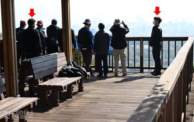 19일 서울 남산공원 전망대에서 시민들이 한남동 관저 쪽을 촬영하려 하자 경호원(붉은색 화살표)이 다가와 제지하고 있다. 고영권 기자
