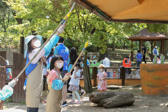 동아제약의 세이브투세이브 캠페인 일환으로 지난 6월 실시된 서울대공원 동물원 벽화 그리기 자원봉사활동에서 임직원 가족들이 봉사를 하고 있다.  동아제약 제공.