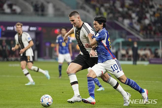 [도사=뉴시스/AP] 일본 대표팀 공격수 미나미노 다쿠미가 2022 카타르 월드컵 독일과의 조별리그 첫 경기에서 볼 경합을 벌이고 있다. 2022.11.23