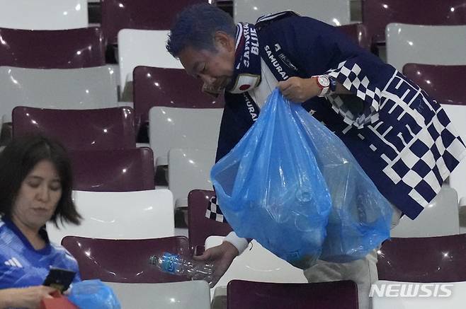 [알라이얀(카타르)=AP/뉴시스]쓰레기를 줍고 있는 일본 축구 팬