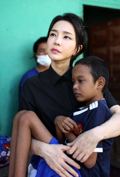 윤석열 대통령의 부인 김건희 여사(앞줄 왼쪽)가 지난 12일 캄보디아 수도 프놈펜에서 선천성 심장질환을 앓고 있는 14세 아동의 집을 찾아 아이를 안고 있다. 프놈펜=뉴스1