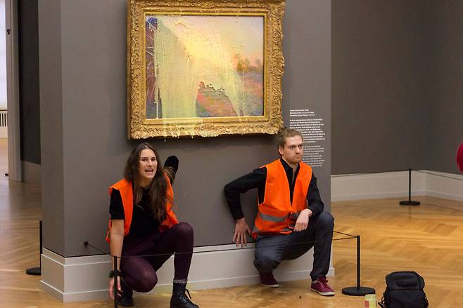 독일 기후단체 '라스트 제너레이션'(Last Generation) 활동가들이 10월24일 독일 바르베리니 박물관에서 클레드 모네의 작품 '건초더미'(Les Meules)에 으깬 감자를 던진 뒤 미술관 벽에 자신들의 손을 접착제로 고정하는 퍼포먼스를 벌이고 있다.ⓒ연합뉴스