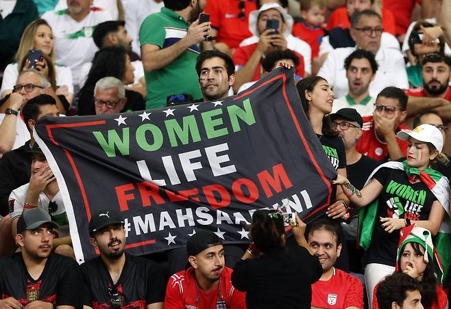 지난 21일 이란과 잉글랜드의 경기에서 이란을 응원하는 관중이 '여성, 생명, 자유'라고 적힌 플래카드를 들어보이고 있다. /로이터 뉴스1