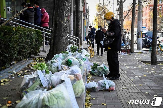 중국 베이징의 한 배달기사가 25일 코로나19 확진자 증가로 봉쇄된 일부 지역의 주민들에게 배달될 식료품을 내려다보고 있다.  /AFPBBNews=뉴스1