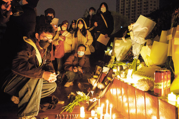 24일 밤 중국 북서부 신장 우루무치에서 화재가 발생해 주민 10명이 사망한 가운데, 27일 베이징에서 시민들이 희생자들을 추모하기 위해 모여 있다.베이징, 상하이 등 중국 주요도시에서 코로나19 고강도 봉쇄에 항의하는 시위가 들불처럼 번지고 있다. [로이터]