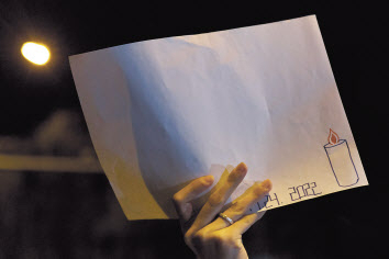 27일 중국 베이징에서 시위에 참석한 한 여성이 정부의 검열에 항의하는 의미로 백지를 들고 있다. 하단에는 신장 우루무치에서 화재가 발생해 10명의 희생자가 발생한 날짜가 쓰여 있다. [로이터]