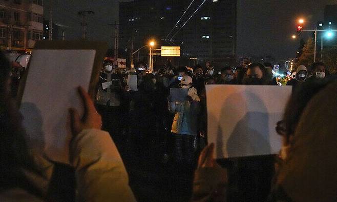 지난 27일 중국 베이징에서 코로나19 봉쇄 정책에 항의하는 시위대가 '백지'를 들고 구호를 외치고 있다. 시민들은 정부에 항의하는 의미를 담은 ‘백지’를 들고 28일 새벽까지 시위를 이어갔다. AP뉴시스