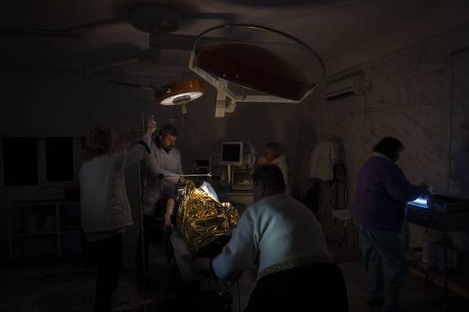 지난 22일(현지시간) 남부 헤르손의 한 병원 의사들이 어두운 수술실에서 러시아군 공격에 부상당한 13세 남자 어린이의 왼쪽 팔 절단 수술을 하고 있다. 사진=AP·연합뉴스