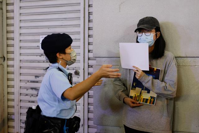28일(현지시간) 홍콩에서 중국 신장위구르자치구 우루무치시에서 화재로 목숨을 잃은 이들을 추모하고 중국 당국의 '제로 코로나' 정책을 비판하는 백지 시위에 나선 한 여성이 경찰의 퇴거 요청을 받고 있다. 로이터 연합뉴스