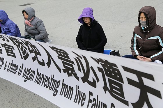 파룬궁 수련자들이 미국 뉴욕의 중국 영사관 앞에서 중국 당국의 탄압에 항의하는 현수막을 앞에 두고 명상을 하고 있다. [AP 연합뉴스]