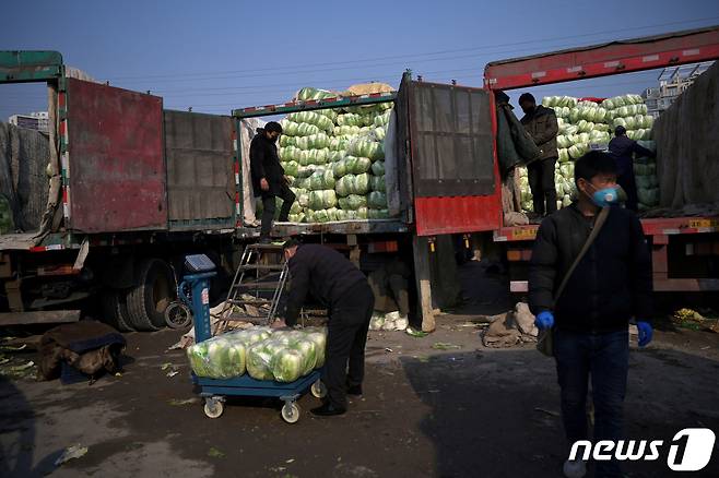 중국 베이징 농산물 도매시장에서 코로나19가 발생하자 마스크를 쓴 사람들이 배추를 옮기고 있다. 2020.02.19 ⓒ 로이터=뉴스1 ⓒ News1 권진영 기자