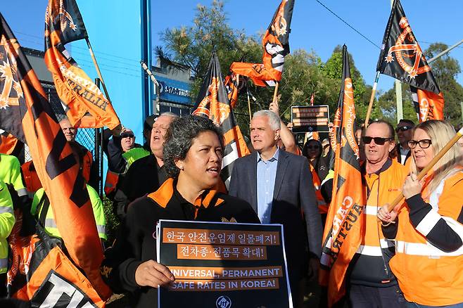 2021년 10월 오스트레일리아 운수노조의 파업 현장에서 한 참가자가 한국 내 안전운임제 확대를 요구하는 팻말을 들고 있다. ⓒ임월산 제공