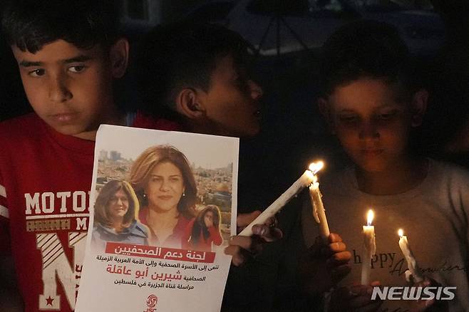 [가자시티=AP/뉴시스] 11일(현지시간) 팔레스타인 가자 시티의 알자지라 네트워크 앞에서 팔레스타인 어린이들이 시린 아부 아클레(51) 기자의 사진과 촛불을 들고 있다. 아부 아클레 기자는 요르단강 서안 제닌시에서 취재 중 이스라엘군의 총격에 머리를 맞아 숨졌다. 알자지라는 이스라엘 군인들이 아부 아클레를 의도적으로 살해했다며 국제사회가 이스라엘에 책임을 물어야 한다고 주장했다. 2022.05.12.