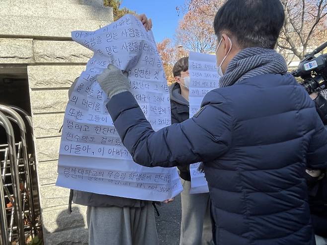 ‘대현동 이슬람사원 건립 반대 비대위’가 15일 대구 북구 경북대 서문에 경북대 재학생과 졸업생 2명이 비대위의 돼지고기 행사를 비판하는 대자보를 붙이려고 하자 항의하고 있다. (사진=연합뉴스)