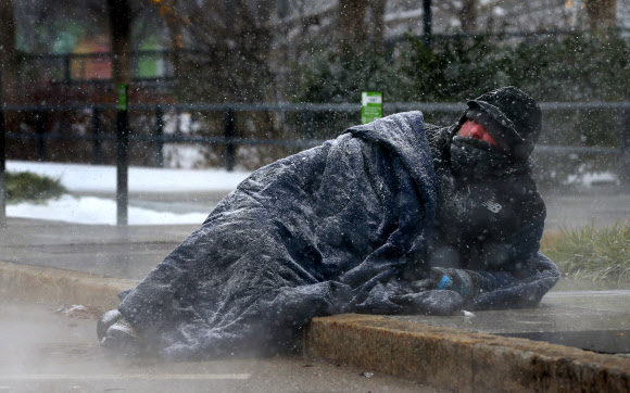 미 미주리주 세인트루이스의 키러 플라자 근처에서 한 노숙인이 맨홀 뚜껑에서 나오는 따뜻한 증기로 몸을 녹이려 하고 있다. AP연합뉴스