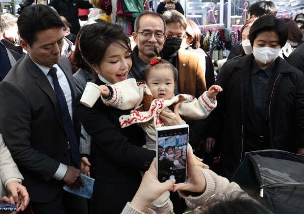 김건희 여사가 11일 대구 서문시장에서 아이를 안고 촬영에 응하고 있다. 연합뉴스