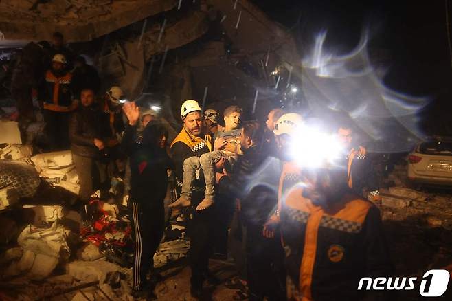 6일(현지시간) 시리아 다나에서 구조대원들이 어린 생존자를 구조해 안전한 곳으로 옮기고 있다. ⓒ AFP=뉴스1 ⓒ News1 권진영 기자