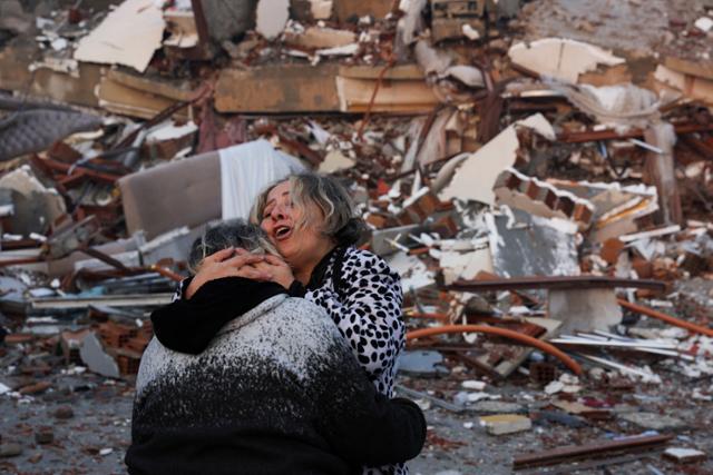 7일 지진으로 붕괴한 튀르키예 하타이의 건물 잔해 앞에서 생존자 두 명이 서로를 끌어안고 있다. 하타이=로이터 연합뉴스