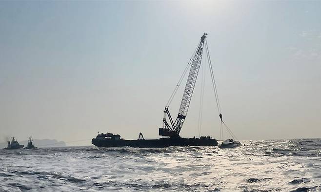 7일 전남 신안 해상에서 전복된 24t급 통발어선 청보호가 대형 크레인선에 묶여 안전지대로 옮겨지고 있다. 연합뉴스