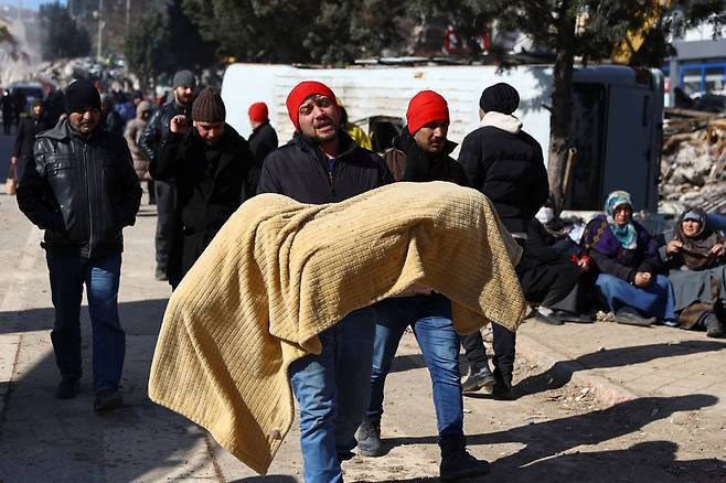 8일 튀르키예 카흐라만마라슈 지진 피해 현장에서 한 남성이 희생자의 시신을 안아 옮기고 있다./로이터 뉴스1
