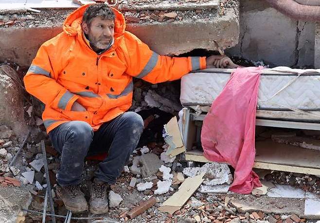 7일(현지시간) 튀르키예 남동부 카흐라만마라슈의 무너진 건물 잔해에서 메수트 한제르라는 남성이 잔해 속의 숨진 15세 딸 손을 붙잡고 있다. 카흐라만마라슈=AFP연합