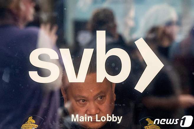 A security guard looks out a door as customers line up at Silicon Valley Bank headquarters in Santa Clara, California on March 13, 2023. (Photo by NOAH BERGER / AFP) ⓒ AFP=뉴스1