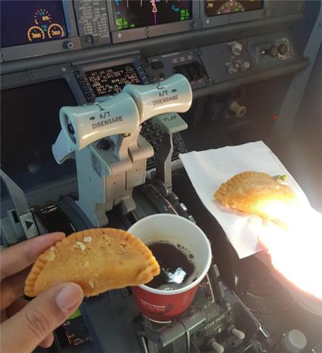 인도 스파이스제트 항공 조종사 2명이 튀김만두를 손에 쥐고 있다. 비행기 추력 레버 옆에는 커피가 놓여있다. 트위터 캡처