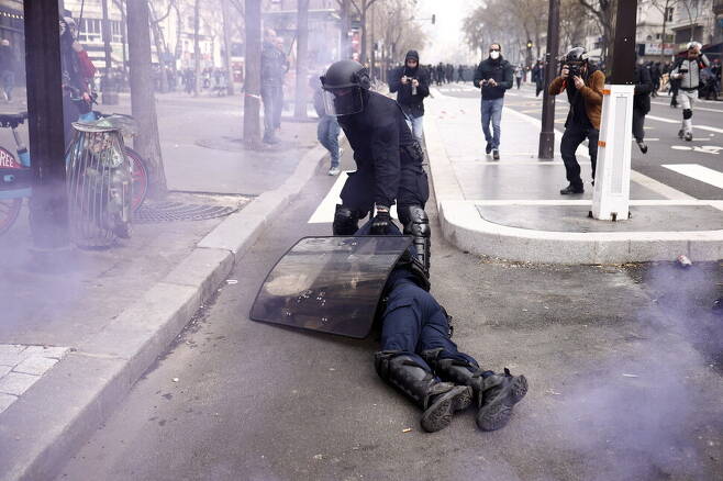 경찰이 23일(현지시각) 프랑스 파리 연금개혁 반대 시위 진압 도중 다친 동료를 병원으로 이송하기 전 방패로 보호하고 있다. 파리/EPA 연합뉴스