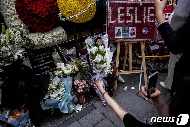 홍콩의 가수 겸 배우였던 장국영의 사망 20주기를 맞은 1일(현지시간) 홍콩에서 시민들이 길가에 놓인 추모 화환과 그의 생전 모습을 카메라에 담고 있다. 2023.04.01. ⓒ AFP=뉴스1 ⓒ News1 김성식 기자