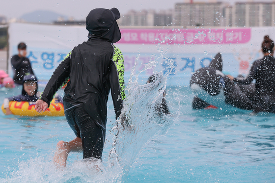 Children wearing rash guards splash around at Yanghwa Swimming Pool in Yeongdeungpo District, western Seoul on Aug. 4, 2022. [YONHAP]