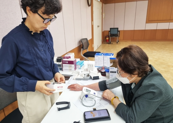 서울 구로구가 ‘인공지능·사물인터넷 기반 어르신 건강 관리 사업’을 선보인 가운데 방문 간호사(왼쪽)가 이 사업에 참여한 어르신의 혈압을 확인하고 있다. 구로구 제공