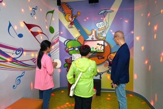 둘리 주제곡을 직접 불러볼 수 있는 마이콜 뮤직 스테이지에서 노래를 부르고, 탬버린을 치고 있는 소중 학생기자단.