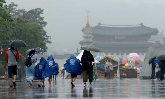 부처님 오신 날 연휴를 맞아 빗줄기가 이어지는 가운데 28일 서울 세종대로 광화문광장에서 우산을 쓰고 우비를 입은 시민과 관광객들이 오가고 있다. 연합뉴스