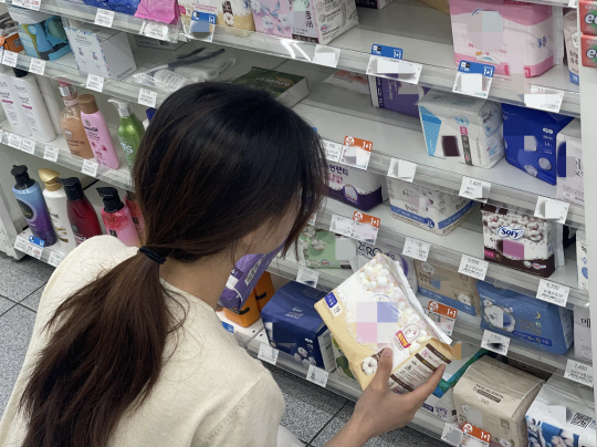 29일 대전 서구 월평동의 한 편의점에서 시민이 생리대 구매를 위해 가격을 비교하고 있다. 사진=최다인 기자