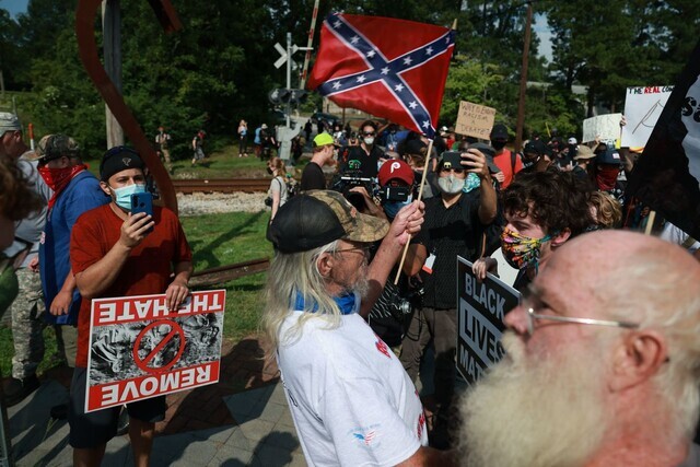 지난 2020년 8월15일 미국 조지아주 스톤 마운틴 시내 근처에서 한 남성이 인종차별 반대 시위 군중을 향해 남부연합기를 흔들고 있다. AFP 연합뉴스