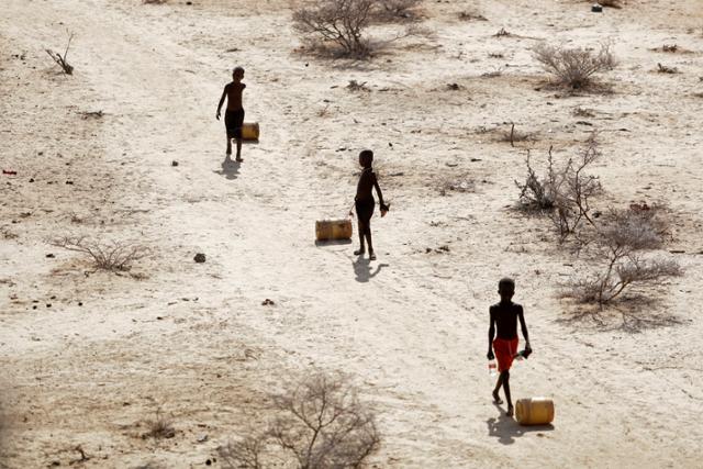 지난해 10월 아프리카 케냐 은타바시(Ntabasi) 지역의 소년들이 40년만의 가뭄으로 부족해진 식수를 얻기 위해 우물에서 자신들의 오두막 집으로 물통을 옮기고 있다. AP 연합뉴스