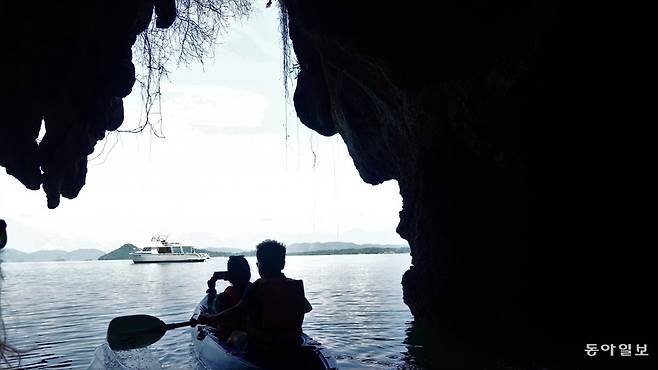 카약을 타고 바다 동굴을 탐험한 후 유람선으로 되돌아가는 관광객. 안영배 기자
