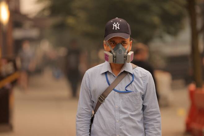 캐나다에서 발생한 산불 연기가 미국의 동부 지역까지 확산하는 가운데 7일(현지 시각) 한 남성이 방진 마스크를 쓴 채 뉴욕 거리를 걷고 있다. 이날 미국 환경보호청(EPA)은 1억명 이상의 주민에게 대기질 경보를 발령했다.