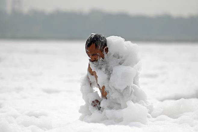 세계 환경의 날을 하루 앞둔 6월 4일 인도 뉴델리의 거품이 가득한 야무나 강의 오염된 물에서 한 남성이 목욕을 하고 있다./AFP 연합뉴스