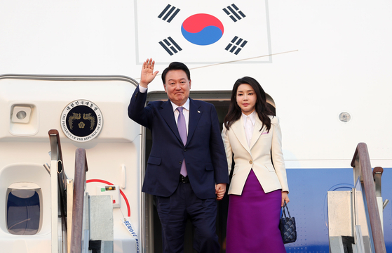 President Yoon Suk Yeol, left, waves, alongside first lady Kim Keon-hee after arriving on the presidential jet at Seoul Air Base in Seongnam, Gyeonggi, wrapping their six-day trip to Paris and Hanoi on Saturday evening. [JOINT PRESS CORPS]