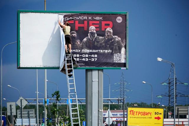 24일 러시아 상트페테르부르크의 고속도로 변에 설치된 입간판에서 '바그너 용병그룹에 들어오라'는 문구가 적힌 용병 모집 포스터가 제거되고 있다. 상트페테르부르크=AP 뉴시스