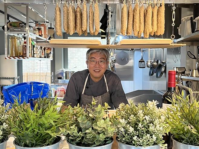 한겨레에서 디자인팀장을 지낸 임호림 육림델리카트슨 대표가 지난 23일 서울 양천구 목동 자신의 가게 안에서 포즈를 취하고 있다. 위에 살라미 소시지가 보인다.