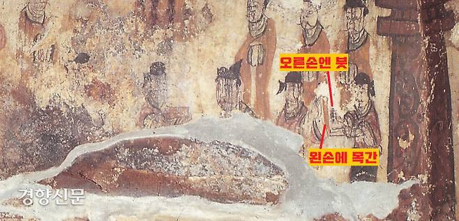 맨 오른쪽 인물은 왼손엔 목간, 오른쪽엔 붓을 들고 옆 사람이 전달하는 이야기를 열심히 받아적고 있다. 기자(기록자)의 모습이다.