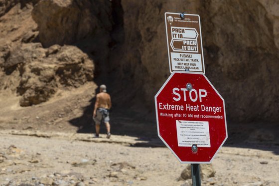 한 등산객이 지난 11일 미국 캘리포니아주 데스밸리 국립공원에서 극심한 더위를 경고하는 표지판을 지나고 있다. AP=연합뉴스
